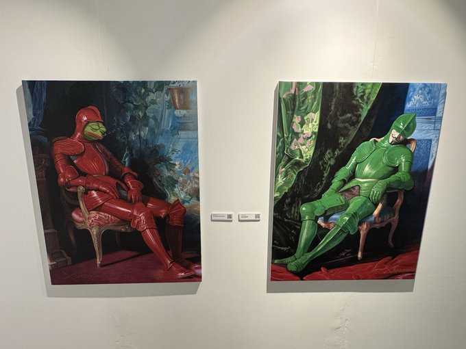 Two paintings displayed on a white gallery wall depict figures in full bodysuits—one red, one green—seated in ornate chairs against richly patterned backgrounds.