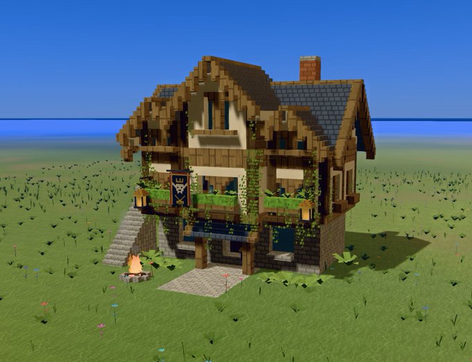 A detailed Minecraft build of a two-story medieval-style house with timber framing, a slate roof, vines, and a small campfire in front, set in a grassy plains biome.