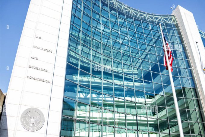 A photograph of the U.S. Securities and Exchange Commission building, showing its modern glass facade, stone exterior with engraved lettering, and the official seal, with an American flag flying nearby.