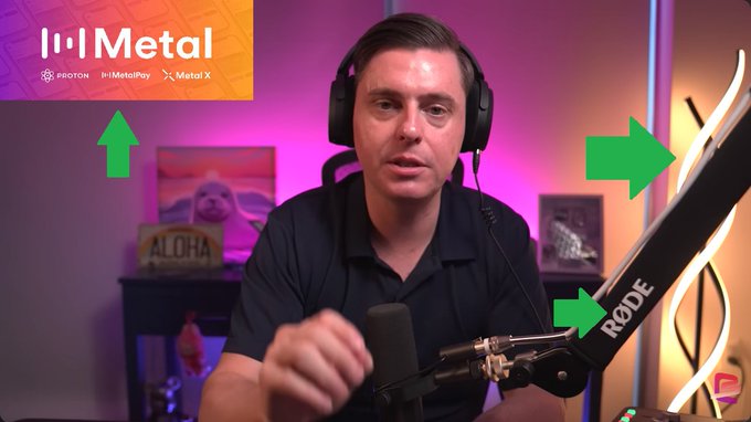 The image features a man wearing headphones, sitting at a desk with a microphone in front of him. The background includes a purple wall and a lamp that has "XRP" written on it. There are also two arrows pointing towards the microphone, suggesting some sort of direction or guidance for the viewer. The post seems to be promoting XRP as a foundationally built product from protons, which is related to the man's presence in front of the microphone and the purple wall behind him.