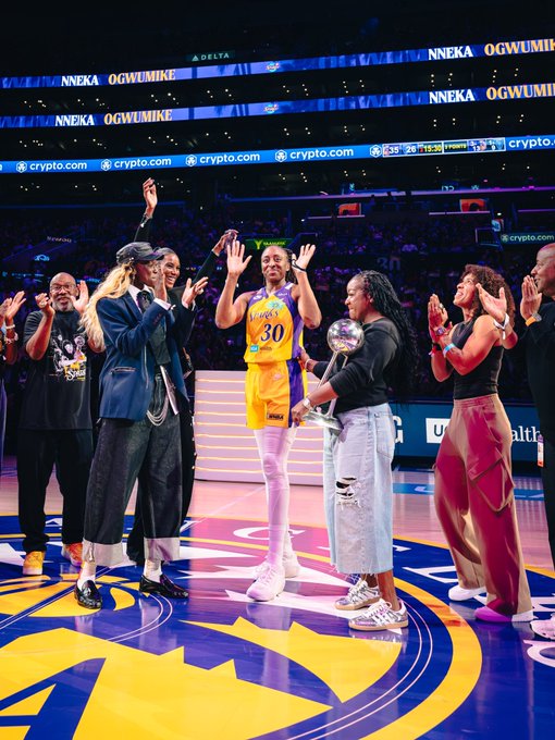 Nneka Ogwumike (jersey #30) of the Los Angeles Sparks stands at center court with the championship trophy as her family and teammates applaud her achievement at the Crypto.com Arena, honoring her recognition as team president.