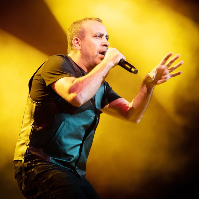 A male singer performs on stage with a microphone against a yellow backdrop, likely illustrating a lost opportunity contrasted with the post's mention of #ARB, #EIGEN, #TIA, and 5 million₺.