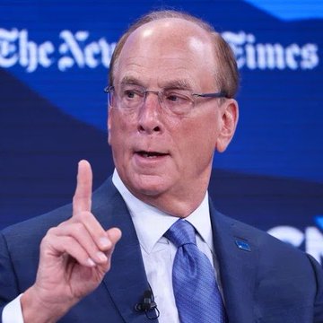 Larry Fink, CEO of BlackRock, is shown speaking at a New York Times event while gesturing with his index finger raised. The image relates to the post about BlackRock's deposit of 951.5 BTC ($59 million) into Coinbase, highlighting the asset management firm's continued involvement in Bitcoin trading activity.