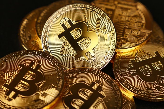 A close-up of several gold Bitcoin physical tokens featuring the iconic "B" symbol and inscriptions like "BITCOIN DIGITAL DECENTRALIZED PEER TO PEER" and "FINE COPPER." The image visually represents the cryptocurrency transactions that Argentina will begin automatically sharing with foreign tax authorities under the new reporting framework by September 2029.