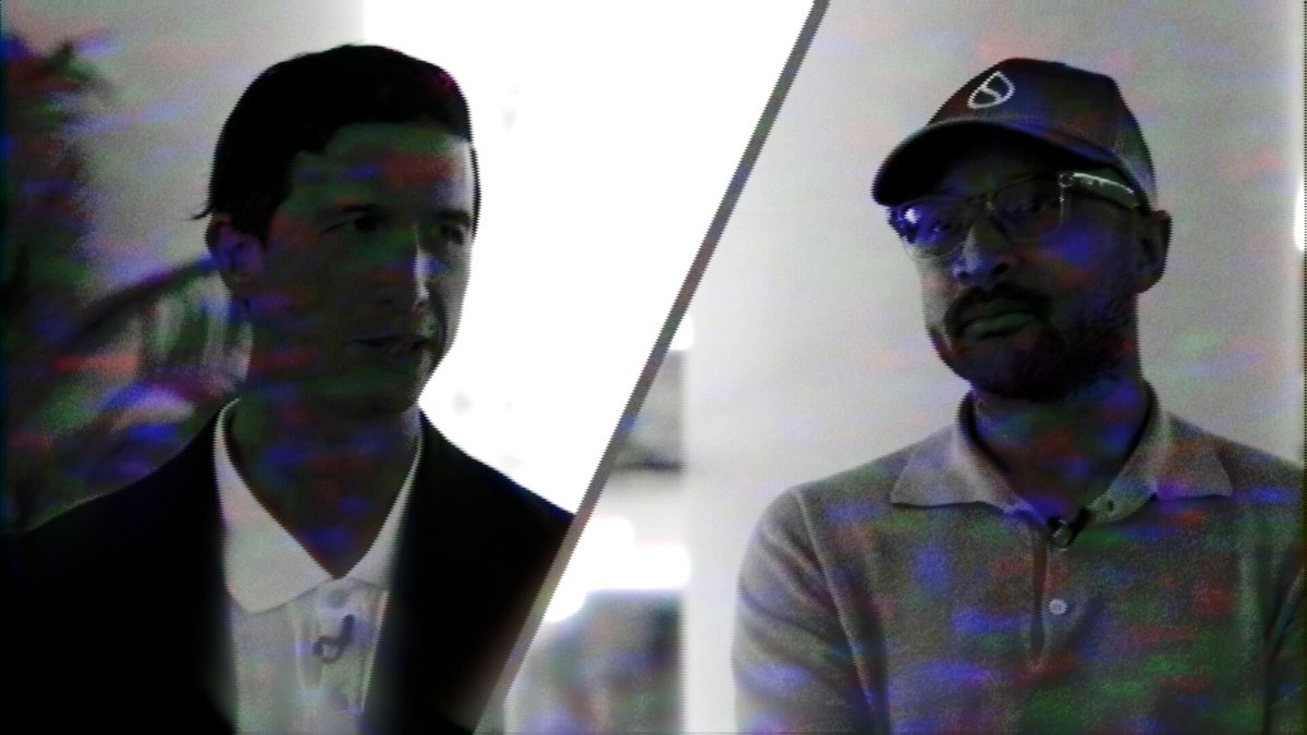 The image shows two men wearing suits, with one man wearing a hat. They are standing next to each other against a white background. The photo has been edited or altered, giving it a vintage appearance. The caption of the image reads "“We responded with a paper that shows it'S absolutely possible. And it's running now.” @EmanAbio Co-founder & CPO @Mysten_Labs shares to @_dsencil how #Sui proved otherwise at @Consensus2026 Miami."
