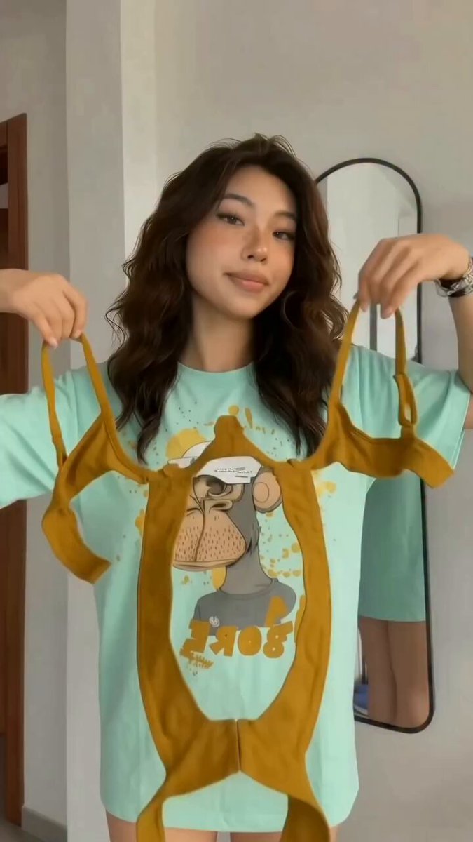 The image features a woman wearing a green t-shirt with an image of a monkey on it, holding two yellow straps that appear to be underwear. The background includes a mirror and a door, suggesting that she might be in her bedroom or dressing room area. The caption "Bored Apes to 100ETH again" implies that the woman is sharing this image as part of a series of posts about monkeys.