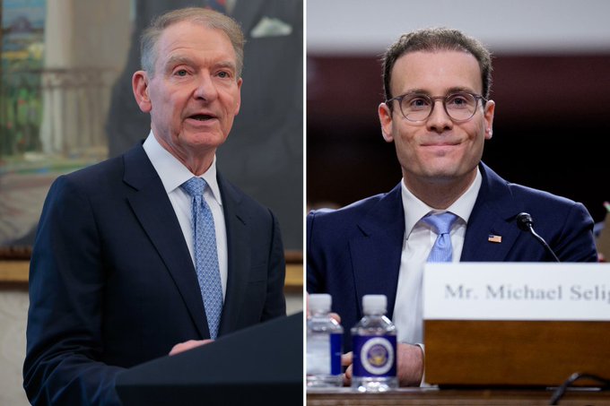 The picture shows two prominent financial regulators: former SEC Chairman Paul Atkins (left) and CFTC Chairman Mike Selig (right), as identified by the visible name placard reading "Mr. Michael Seli[g]." Their presence in the image relates to the accompanying post about a White House crypto meeting chaired by President Trump, where Atkins and Selig are key attendees as leaders of the SEC and CFTC, respectively—the agencies central to U.S. crypto regulation amid the stalled CLARITY Act.