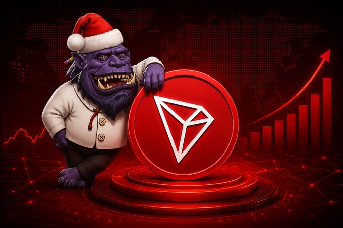 In this image, a cartoon character wearing a Santa hat is standing next to a round coin with the trường symbol on it. The character appears to be holding or leaning against the coin while it's on display. The background of the image features a dark color and has various red shapes and lines scattered throughout. Additionally, there is text that reads "TRON vẫn đang cho thấy sự ổn định giữa lúc trường biến đây không xuất phát từ bất kỳ thông tin tiêu cực nào liên quan đến hệ sinh trường", which is related to the cartoon character and the round coin. The post appears to be discussing the coin or a similar theme, possibly drawing attention to this particular item in the image.