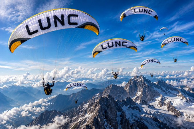 Multiple paragliders soar over snow-capped mountain peaks beneath a bright blue sky, each canopy boldly branded with the "LUNC" ticker, visually echoing the post's "#LUNC we'll fly higher" message of soaring momentum.