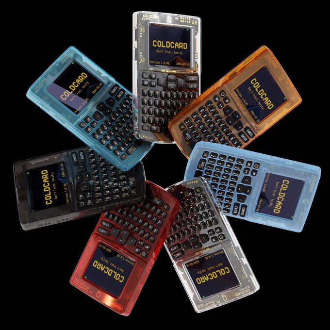 An arrangement of seven colorful translucent Coldcard hardware Bitcoin wallets displayed against a black background, with each device's screen reading "COLD CARD - Don't Trust, Verify - Version 5.4.9 - 2024-12-31." The image visually represents the Coldcard wallets referenced in the post about the $108 million Bitcoin theft, highlighting the irony of a security breach affecting these "trust but verify" devices.