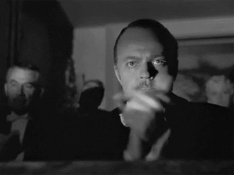 The image shows a man wearing a suit with his hand over his mouth, possibly smoking or blowing his nose. The photo has a vintage appearance, suggesting that it could be from an older time period. The caption provided seems unrelated to the main subject of the image and is not directly related to the content displayed in the picture.