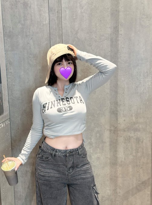 The image features a woman wearing a gray shirt with "Minnesota" printed on it, holding a cup of coffee while posing for a photo. The background consists of a concrete wall or pillar, which adds an urban feel to the scene. The caption provided in the image seems to be unrelated to the main subject and does not provide any additional information about the context or content of the post.
