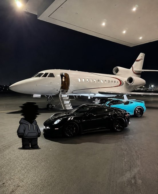 A private jet is parked on a tarmac at night next to a black sports car and a turquoise sports car, with a small cartoon figure added in the foreground.