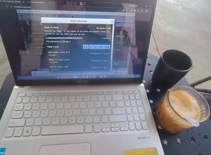 An open laptop on an outdoor table displays a webpage with 'Daily missions' and 'Proof of Viral' text, accompanied by a black coffee cup and a glass of iced coffee.