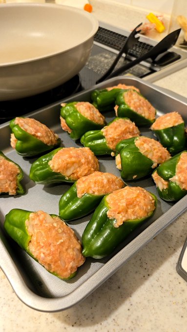 The image shows a tray of food with green peppers, possibly stuffed peppers or stuffed pears, placed on top of an oven rack. The food appears to be cooked and ready for serving.