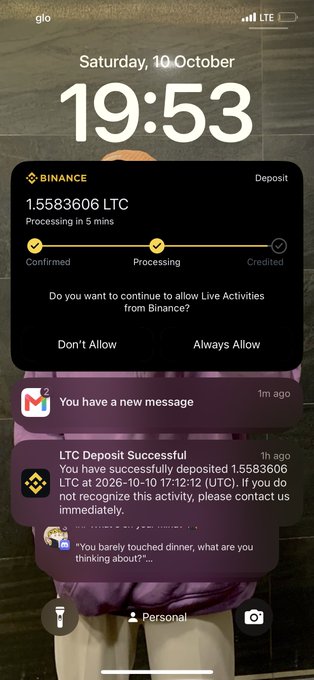 An iPhone lock screen displaying the time '19:53' on 'Saturday, 10 October', with a Binance notification for a 1.5583606 LTC deposit in progress and additional notification banners below.