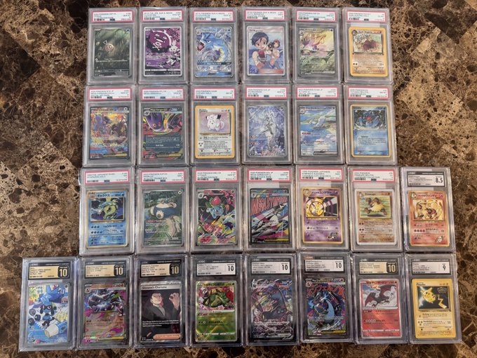 A large collection of graded Pokémon trading cards in PSA slabs, including several Prismatic Evolutions cards and vintage cards, displayed on a rocky surface.