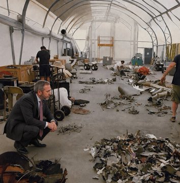 A man in a suit crouches in a large tent filled with scattered debris and remains, while workers in the background sift through the wreckage—creating a stark visual metaphor for the destruction and recovery symbolized by Ripple's perseverance through regulatory hurdles toward the Clarity Act.