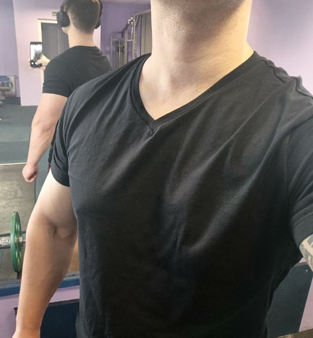 The image features a man wearing a black t-shirt, standing inside a gym with a mirror behind him. The photo captures his reflection as he poses for the camera while holding a green weight. The caption of the image reads "gym Morning, legends! The more time I spend @wallchain ecosystem, the more I start understanding why this project feels genuinely different from many other platforms in the same category A lot of Web3 social / attention projects focus almost entirely on surface-level".