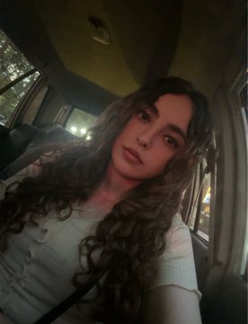 A young woman with long curly hair takes a selfie inside a car at night, gazing directly at the camera in a light-colored top, paired with a morning greeting offering a personal choice for 0.08 ETH, suggesting the photo serves as an intimate, personal introduction to the item or service being sold.