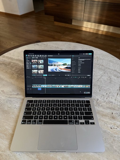 A silver laptop on a stone table with video editing software open on the screen.