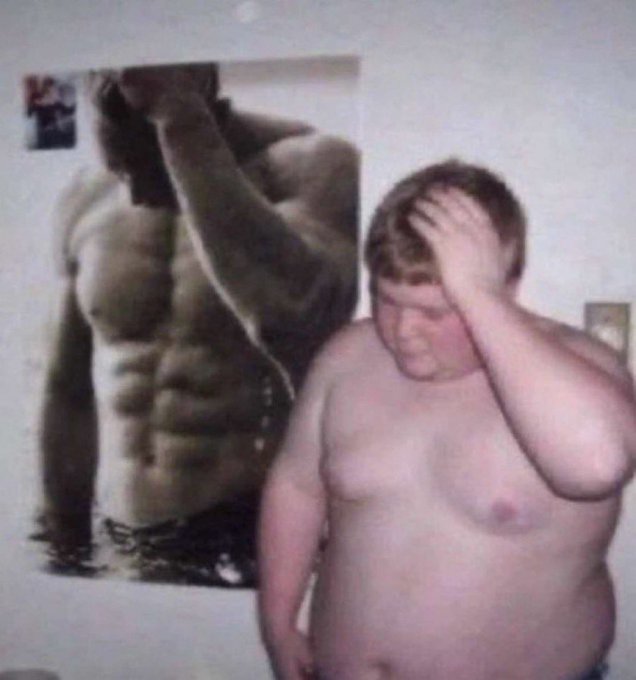 A low-resolution meme-style image of a heavyset shirtless young person standing next to a poster of a muscular shirtless man who appears to be doing a flexing pose, looking down in apparent disappointment.