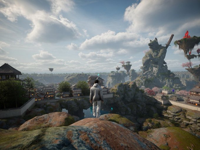 A figure in a white outfit stands on a rocky outcrop overlooking a fantasy landscape featuring traditional East Asian architecture, floating islands, and a colossal stone statue of a cat holding a sword.