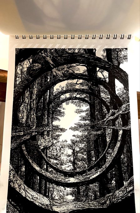 A black-and-white spiral-bound print featuring an intricate mirrored forest scene with circular tree arches creating a kaleidoscopic, tunnel-like effect.