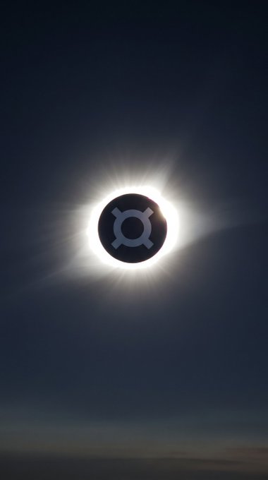 A solar eclipse in the sky with a stylized icon overlaid on the moon's center.