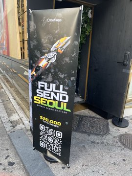 The image features a black and white sign promoting the DeFi app meetup at the DM Lounge in Apgujeong Rodeo. The text of the sign reads "Full Send Seoul", suggesting that this event is focused on sending users to Seoul for an upcoming DeFi meetup. There are also some details about a giveaway contest, including a description of a $30,000 prize and the event's location (DM Lounge in Apgujeong Rodeo). Additionally, there appears to be an item with a qr code displayed, potentially related to the event or promotion.