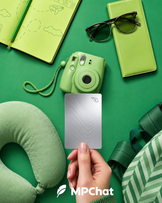 A green-themed flat lay featuring travel accessories including a notebook, sunglasses, camera, neck pillow, and a hand holding an MPChat card.