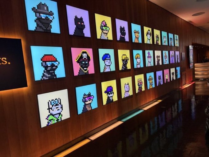 A wall display of CryptoPunks NFT portraits in a modern, warmly lit room with reflective floors.