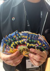 A person wearing a lanyard holding several fans of colorful trading cards in their hands.