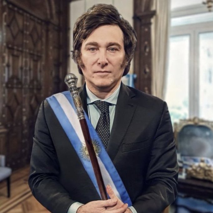 A man in a dark suit wearing the blue and white presidential sash of Argentina holds a ceremonial staff in an ornate room.