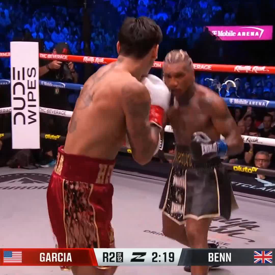 A screenshot from a boxing match between Ryan Garcia and Conor Benn, showing the two fighters in the ring with Garcia in red trunks facing Benn in black and gold trunks, with the scoreboard displaying 'GARCIA' with a US flag and 'BENN' with a UK flag, indicating round 2 of 12 with 2:19 remaining.