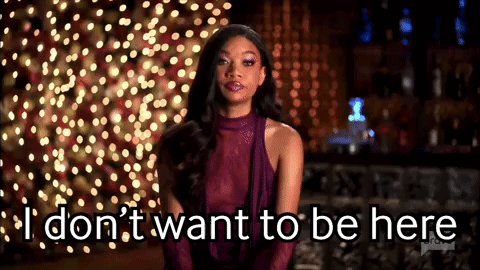 The image features a woman wearing a purple dress, standing against a backdrop of Christmas lights. She has her arms crossed and appears to be looking off into the distance with a serious expression. The text "I don't want to be here" is written above her head in white letters. This phrase seems to be part of a caption or message related to the image, possibly discussing the woman's feelings about being away from home during the holiday season.

The post also includes an image of another person wearing a purple dress and standing against a similar backdrop with Christmas lights. The two women are positioned next to each other in front of a bar, suggesting that they might be at a social event or gathering.