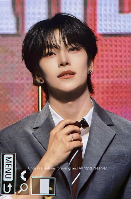 The image features a young man wearing a suit, tie, and earrings standing against a red background with white text. The caption reads "260620 This ridiculously handsome Chinese guy is nuts #XINLONG #鑫隆 #씬롱 #알파드라이브원 포함".