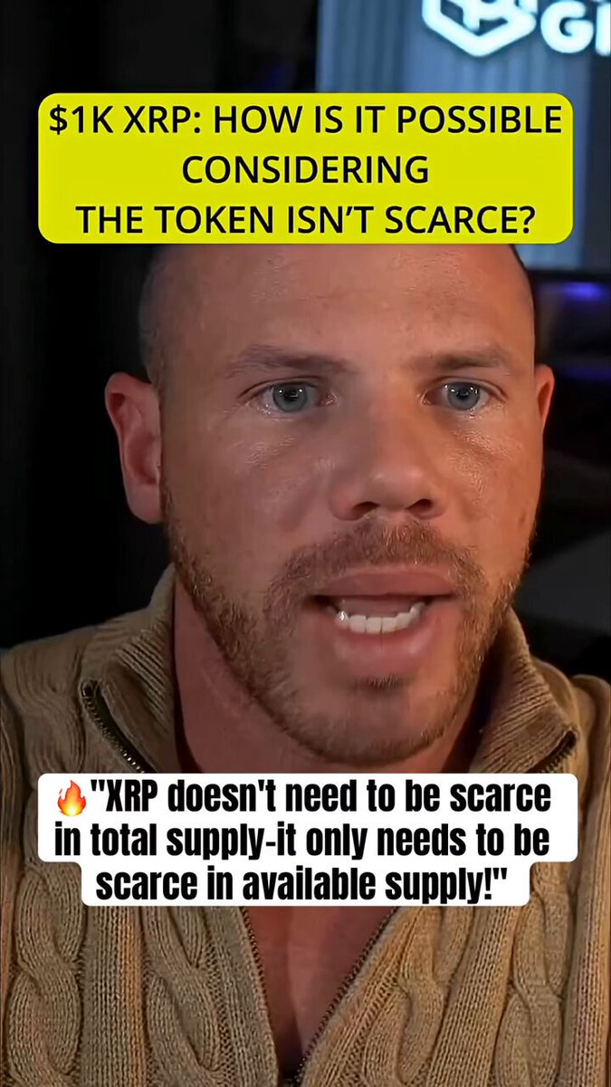 The image shows a man with a beard wearing a brown sweater, speaking or reacting to an event while holding a sign that reads "XRP How is it possible considering the token isn't scarce?".