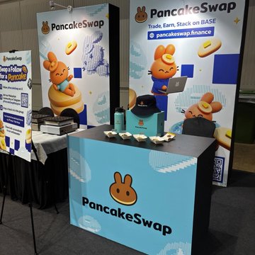 PancakeSwap's branded booth at the Malaysia Blockchain Week features cute bunny mascots and their mascot pancake logo, displaying the text "Trade. Earn. Stack on BASE" alongside the PancakeSwap name and website pancakeswap.finance. The setup includes informational materials on a side table and a blue-branded counter, perfectly matching the post's announcement of their presence at the Base APAC pavilion during Malaysia Blockchain Week in Kuala Lumpur.