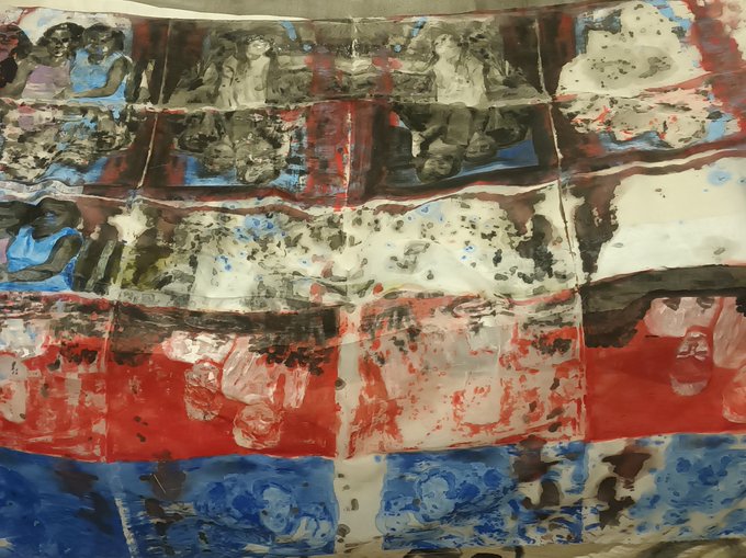 A photograph of a painted artwork or fabric featuring horizontal bands of red, white, and blue with imagery of figures, possibly children, and skull-like faces in a chaotic, expressionist style.