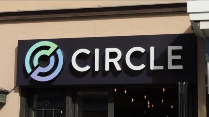 An exterior photograph of a commercial storefront sign for 'CIRCLE' featuring a circular logo with interlocking teal and purple arrows, mounted above the entrance of a building.