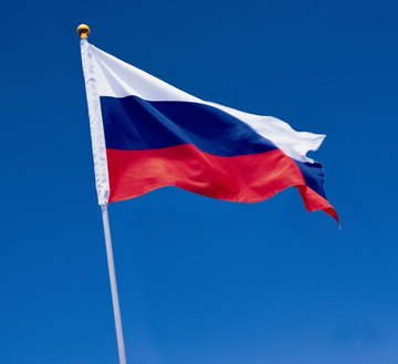 The Russian tricolor flag waves against a clear blue sky. The image likely relates to the post's discussion about Russian public opinion polling on cryptocurrency, suggesting the poll was conducted in Russia given the flag's symbolism.