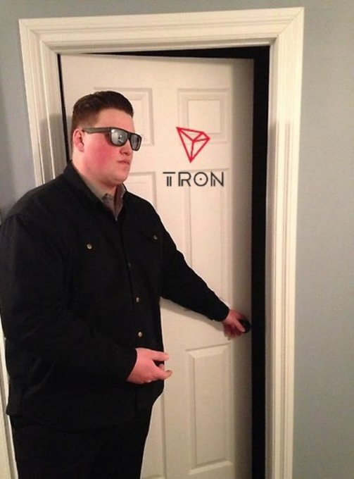 A man wearing dark sunglasses and a black jacket stands in a doorway next to a logo featuring a red diamond shape and the text 'TIRON'.