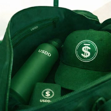 A green USDD-branded pouch contains a bottle and accessories marked with US dollar-style symbols.