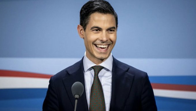 A man in a dark suit and tie stands at a podium, smiling broadly, likely in reference to the Netherlands' new 36% unrealized gains tax legislation set to take effect in 2028.