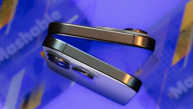 A close-up product render displays a blue smartphone with a square camera module floating against a purple background with partial 'Mashable' text visible.
