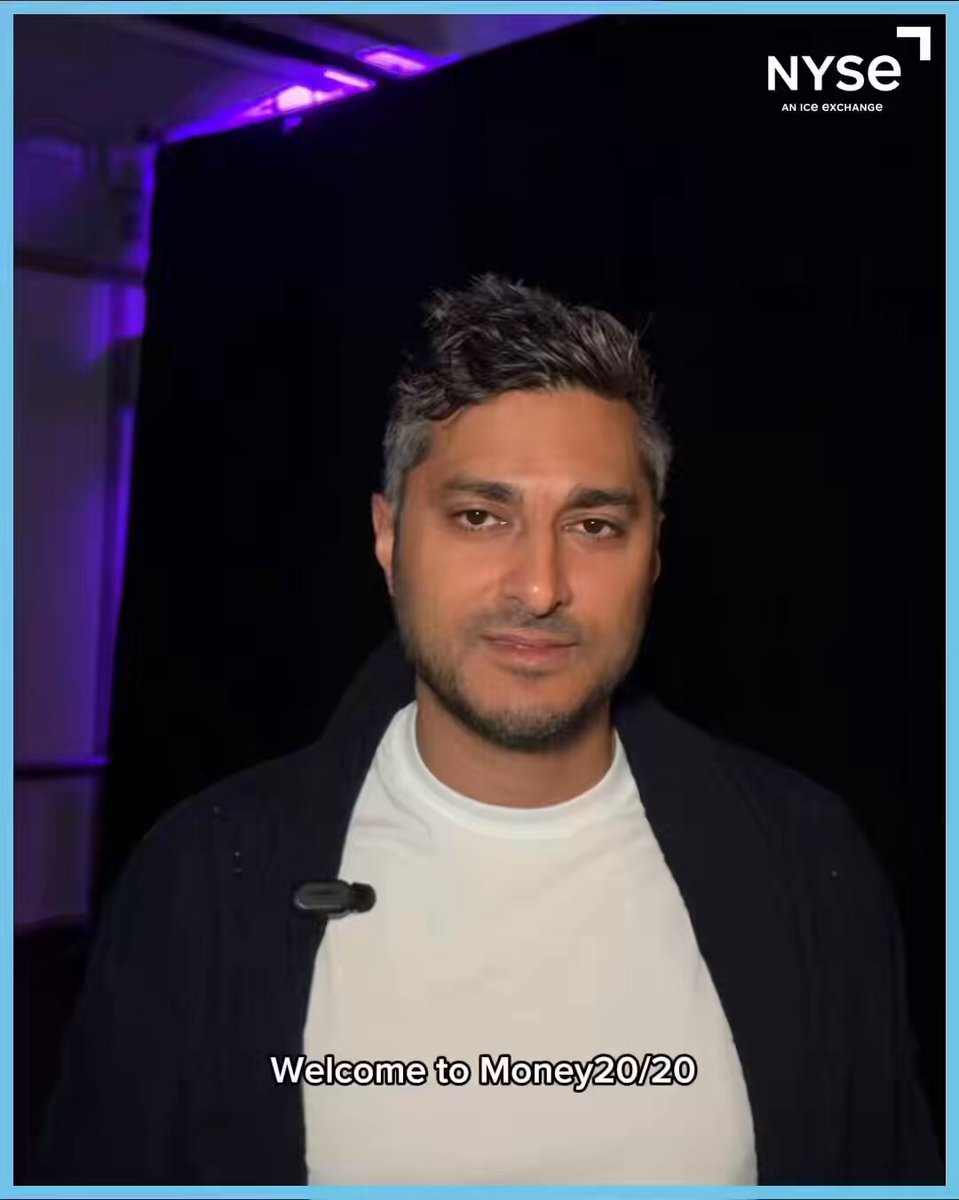 The image features a man wearing a white shirt, standing against a black background with purple lighting. He has short hair and is looking directly at the camera. There are words written below his photo that read "Welcome To Money20/20". The focus of the image seems to be on the man's face rather than the purple lighting or background elements.