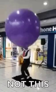 The image features a man dressed as a clown standing in front of a store with a giant purple balloon attached to his head. The caption reads "not this", which seems to be a playful way of pointing out that the clown's costume is not typical for a real-life situation, such as working at a store or performing tricks.