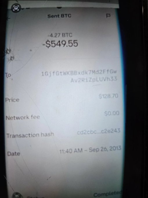 A photograph of a cracked smartphone screen displaying a completed Bitcoin transaction of 4.27 BTC ($549.55) sent to an alphanumeric wallet address, dated September 26, 2013.