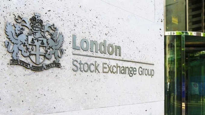 The exterior signage of the London Stock Exchange Group is displayed on a light stone wall, featuring a coat of arms with griffins and the Latin motto 'Dictum Meum Pactum'.